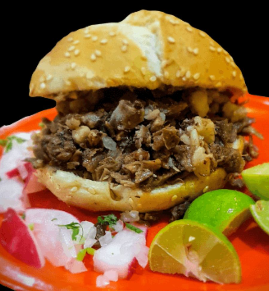 Cema de surtido: pan con ajonjolí relleno de carne de cabeza de res picada, con cebolla, rábano y limones en un plato naranja.